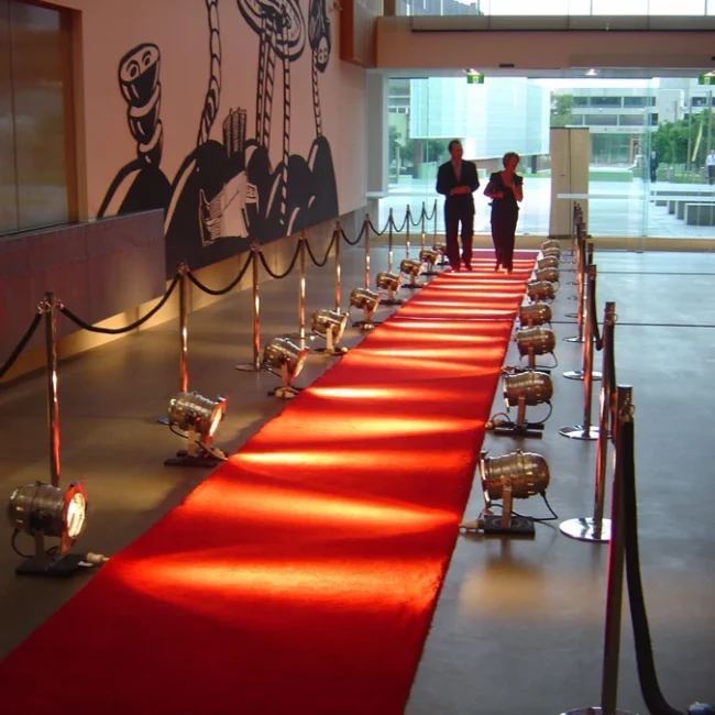 Red exhibition carpet runner illuminated by spotlights